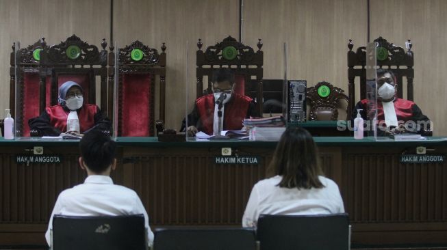 Terdakwa kasus pelanggaran Undang-Undang (UU) ITE Adam Deni (kiri) dan  Ni Made Dwita mengikuti sidang lanjutan dengan agenda pembacaan nota pembelaan atau pledoi di Pengadilan Negeri Jakarta Pusat, Selasa (7/6/2022). [Sheralot.com/Angga Budhiyanto]